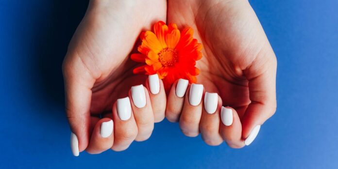 hands-with-white-manicure-on-a-blue-background-with-royalty-free-image-1687976262.jpg