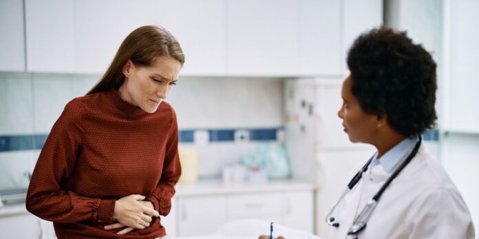 female-patient-holding-her-abdomen-in-pain-while-talking-to-her-doctor-at-medica-clinic.jpg